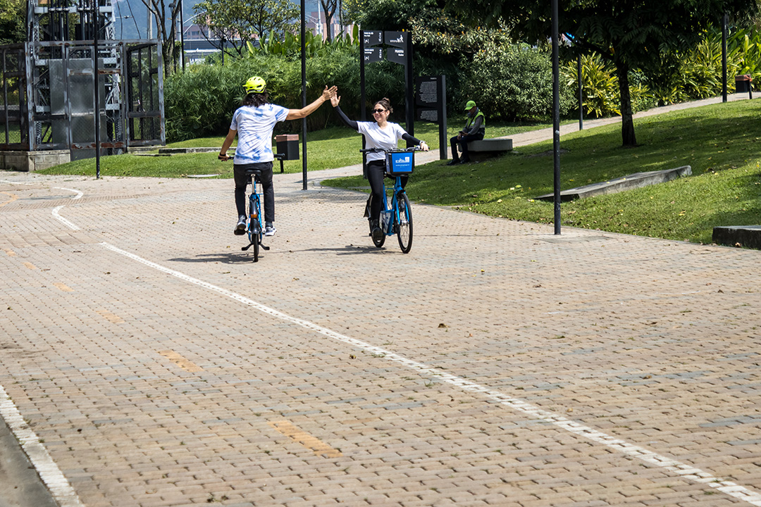 dos usuarios de encicla montando n bicicleta y chocando sus manos